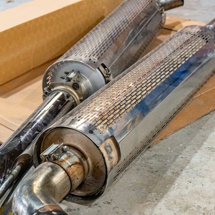 Polished stainless exhaust work laid out in the shop