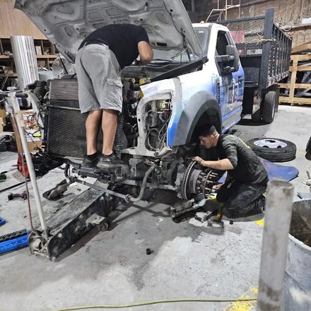 Technicians working under a truck raised on stands