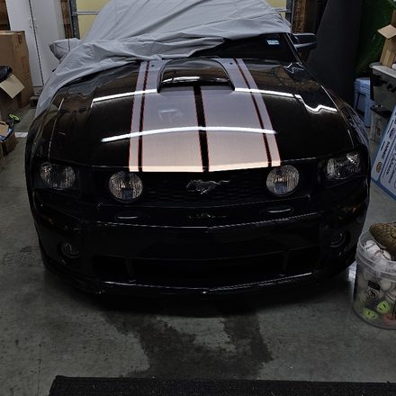 Refinished black paint with white stripes under shop lighting